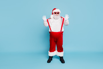 Fototapeta na wymiar Full length photo of funny funky overweight santa claus with big belly abdomen in modern eyeglasses enjoy christmas time newyear party wear overalls red pants boots isolated over blue color background