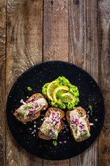 Marinated herring fillets on slices of bread on black stone