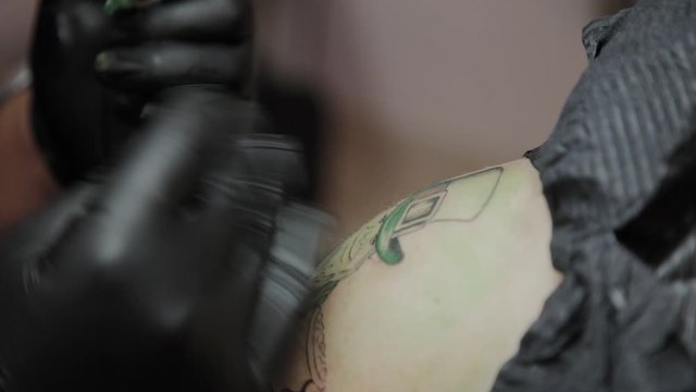 Professional tattoo artist makes a tattoo on a man s arm.