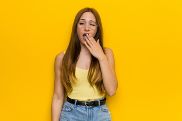 Young redhead ginger woman with freckless yawning showing a tired gesture covering mouth with hand.