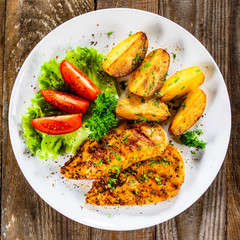 Grilled chicken fillet and vegetableson white plate