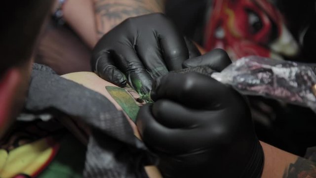 Professional tattoo artist makes a tattoo on a man s arm.