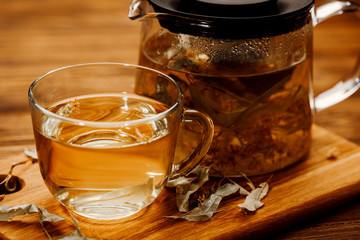 Glass cup of tea with linden on wooden table.