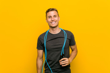 Young caucasian man holding a jump rope happy, smiling and cheerful.