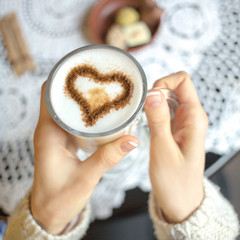Woman holding hot cup of coffee with heart shape. focus on heart