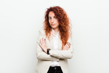 Young natural redhead business woman isolated against white background who feels confident, crossing arms with determination.