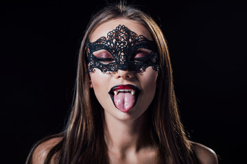 naked scary vampire girl in masquerade mask with fangs showing fangs isolated on black