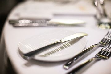 Cutlery, knives, fork and plates on a table in a restaurant before dinner close up