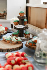 Details of a festival catering: fruits, cupcakes, popcorn and cake. Beautifully decorated table. Delicious candy bar at the wedding ceremony close up. Wedding party concept