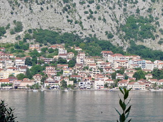 A view from the opposite shore of the bay to a seaside resort town at the foot of a steep cliff covered with poor vegetation.