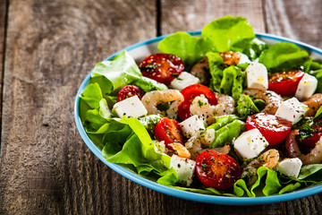 Salad with shrimps and feta cheese on wooden table