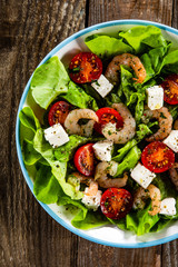 Salad with shrimps and feta cheese on wooden table