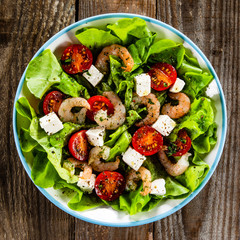 Salad with shrimps and feta cheese on wooden table