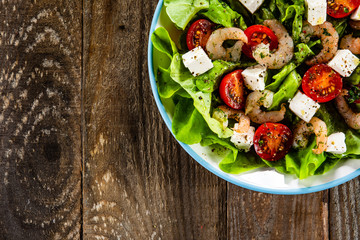 Salad with shrimps and feta cheese on wooden table