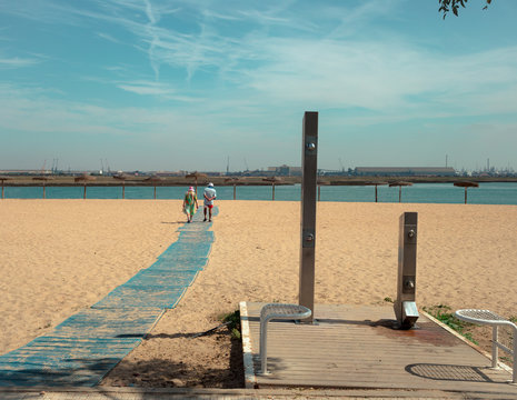 Dos personas caminando por la playa junto las duchas
