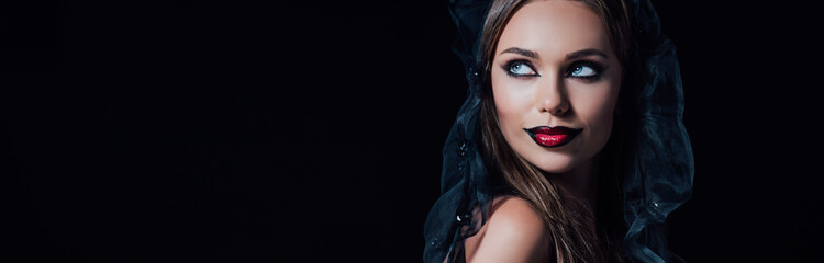 panoramic shot of scary vampire girl in black gothic dress and veil looking away isolated on black