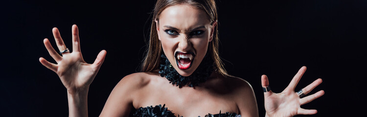 panoramic shot of scary vampire girl with fangs in black gothic dress isolated on black
