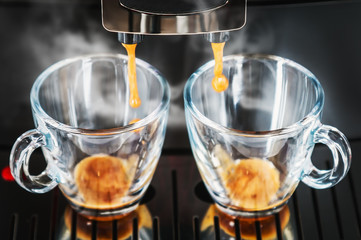 coffee beans are prepared in the coffee machine and poured into glass cups for 2 persons
