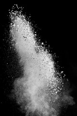 White powder splash isolated on black background. Flour sifting on a black background. Explosive powder white