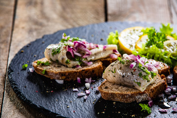 Marinated herring fillets on slices of bread on black stone