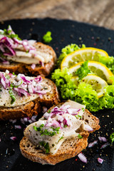 Marinated herring fillets on slices of bread on black stone