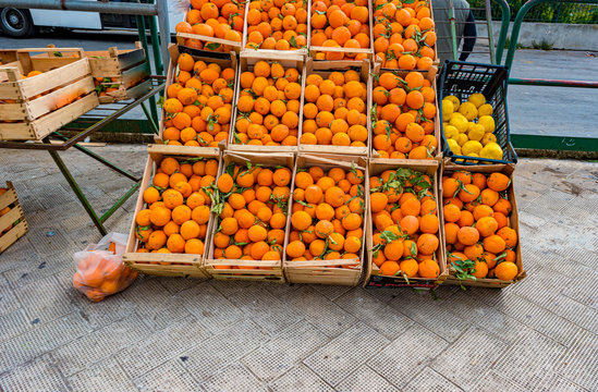 Harvest of oranges in a wooden cart for sale on the market. Mediterranean foofd culture, fresh fruits in the market on the street.