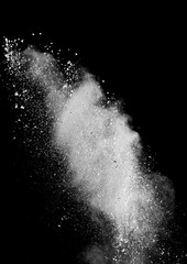 White powder splash isolated on black background. Flour sifting on a black background. Explosive powder white