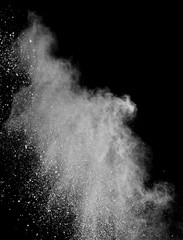 White powder splash isolated on black background. Flour sifting on a black background. Explosive powder white