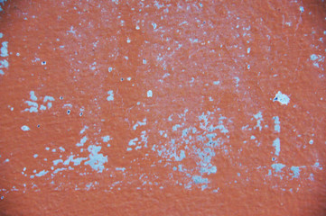 the pink cement wall is old and the surface is peeling off 