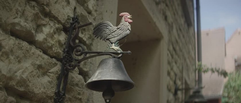 weathercock over an old doorbell - Wetterhahn &uuml;ber einer alten T&uuml;rglocke an einer alten, steinernen Hauswand