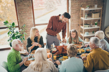 Photo of big family sit feast meals table around roasted turkey father guy making slice for little...
