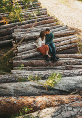Fototapeta premium Love story on the stack of firewood and logs in the autumn forest.