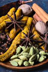 Dry warming Indian spicesin on plate for autumn winter meal on dark close-up.