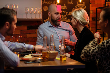 Group of friends playing sticky head game behind bar counter in a cafe