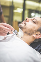 Obraz na płótnie Canvas Fashionable man client during beard shaving in barber shop.