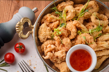  frying pan with seafood in batter served with sweet and sour sauce is on the table