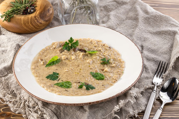 Risotto with porcini mushroom with basil and parsley serving size on wooden table