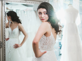 Naklejka premium Beautifu bride choosing wedding dress in a wedding salon