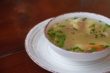 chicken soup in white plate on wooden background