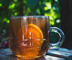 Autumn composition with a transparent cup of tea and lemon. On a natural background. close-up.