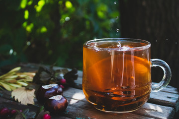 Autumn composition with a transparent cup of tea and lemon. On a natural background. close-up.