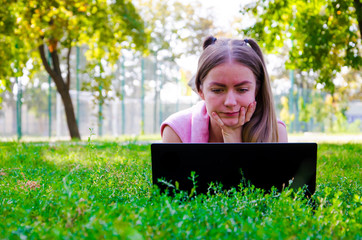 girl lies with a laptop on the grass front view straight summer day