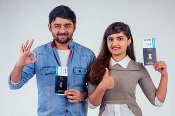 happy indian couple holding passport of India with airline tickets inside in studio white...