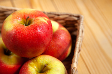 Apple in basket, on wooden background. Water drops. Close-up. Copy space