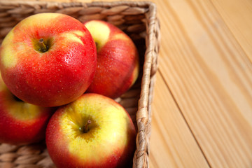 Apple in basket, on wooden background. Water drops. Close-up. Copy space