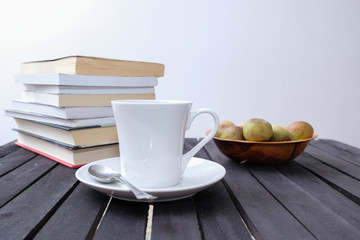 cup of coffee and books and bowl of figs on wooden table