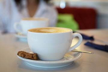 two cups of coffee with cookies on the table in the cafe