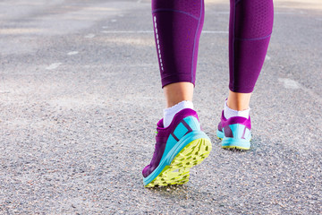 Sporty woman running in sneakers. Runner feet running on road close up on shoe. Young fitness woman running on morning. Fitness and workout wellness concept