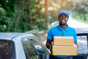 Smile african male postal delivery courier man in the car delivering package