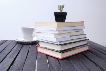 stack of books and coffee cup and cactus on wooden table